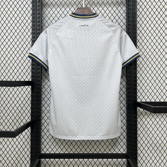 Italy 2026 Away World Cup White Jersey with blue trim hanging on a rack against a grid-patterned wall.