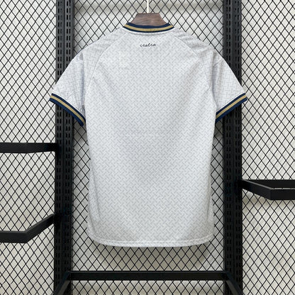 Italy 2026 Away World Cup White Jersey with blue trim hanging on a rack against a grid-patterned wall.