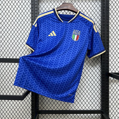 Italy 2026 Home World Cup Jersey - Blue sports jersey with Italian flag logo and Adidas logo on a hanger against a grid background.
