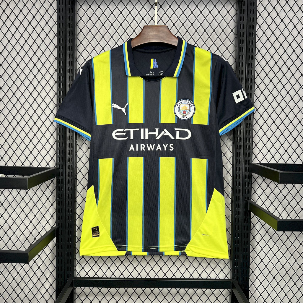 Manchester City 2024/2025 Away Puma Black & Yellow Jersey with 'Etihad Airways' and Puma logos on a hanger against a grid background.