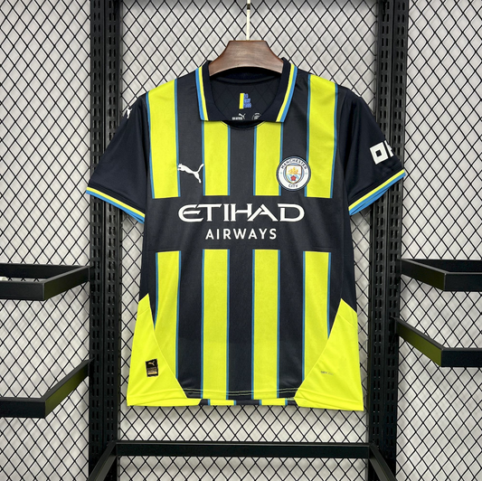 Manchester City 2024/2025 Away Puma Black & Yellow Jersey with 'Etihad Airways' and Puma logos on a hanger against a grid background.
