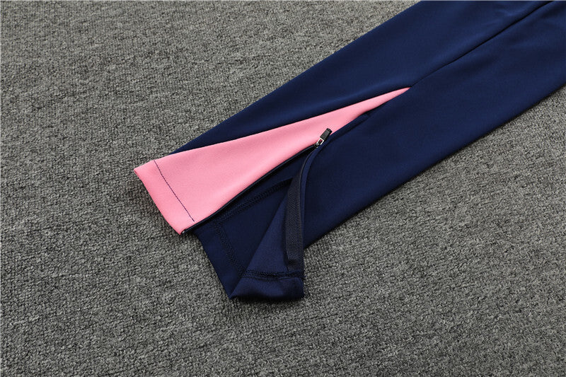 Navy pants of the Nike Atletico Madrid 24/25 Quarter Zip Tracksuit with pink interior lining on a gray textured surface.