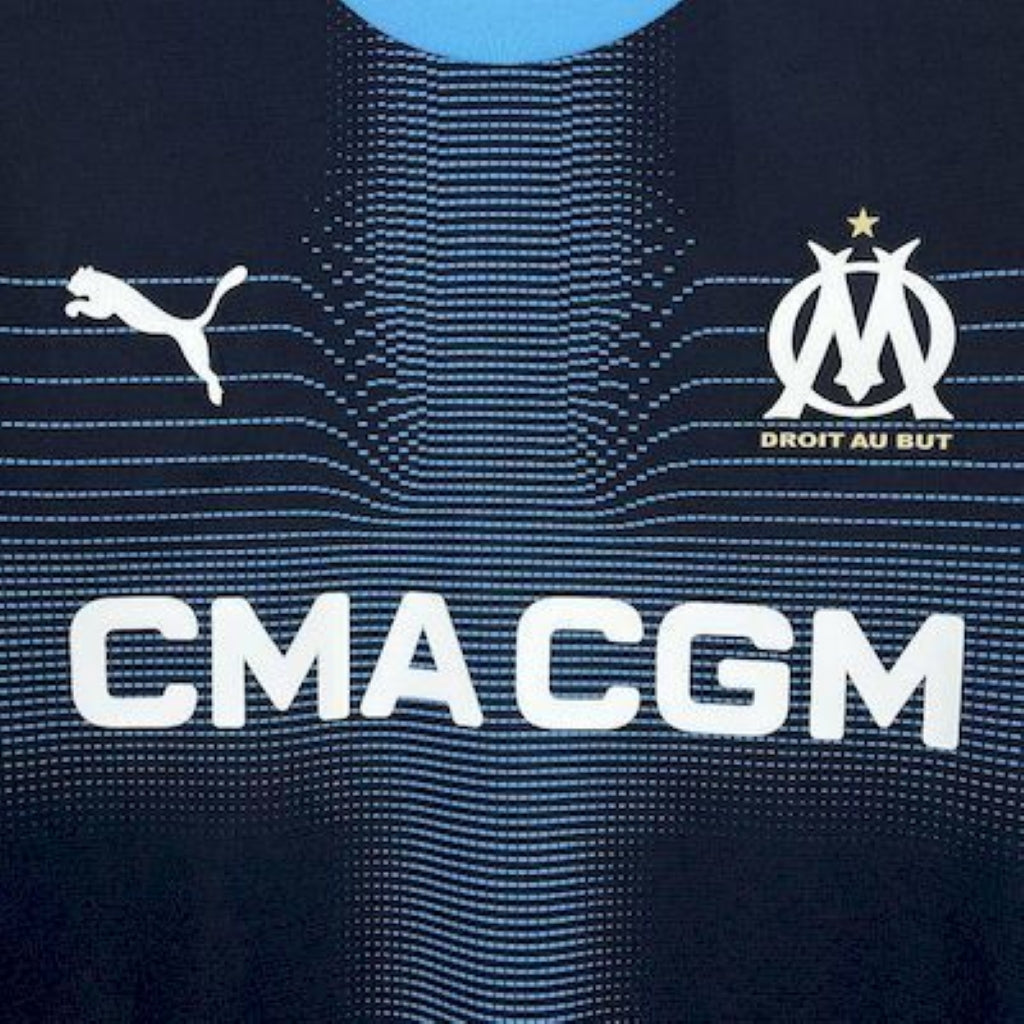 Close-up of Olympique Marseille 25/26 Away Blue sports jersey with Puma and Olympique de Marseille logos.