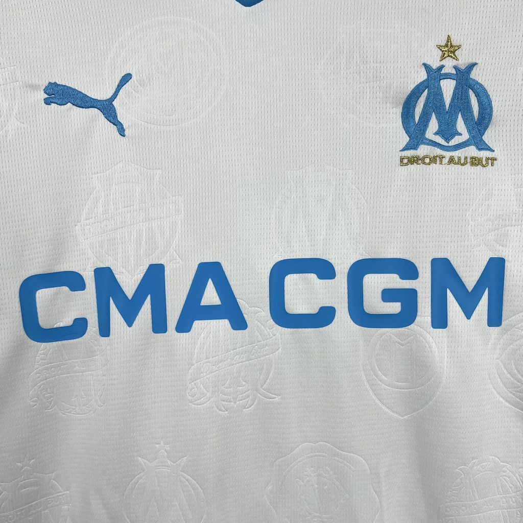Close-up of Olympique Marseille 25/26 Home white sports jersey with Puma and Olympique de Marseille logos, featuring 'CMA CGM' text.