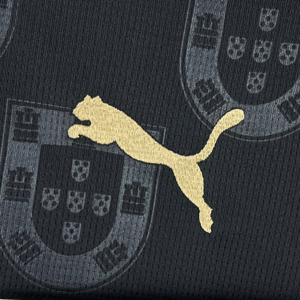 Portugal 2026 Away Jersey - Puma logo on a black fabric with Portuguese coat of arms pattern.